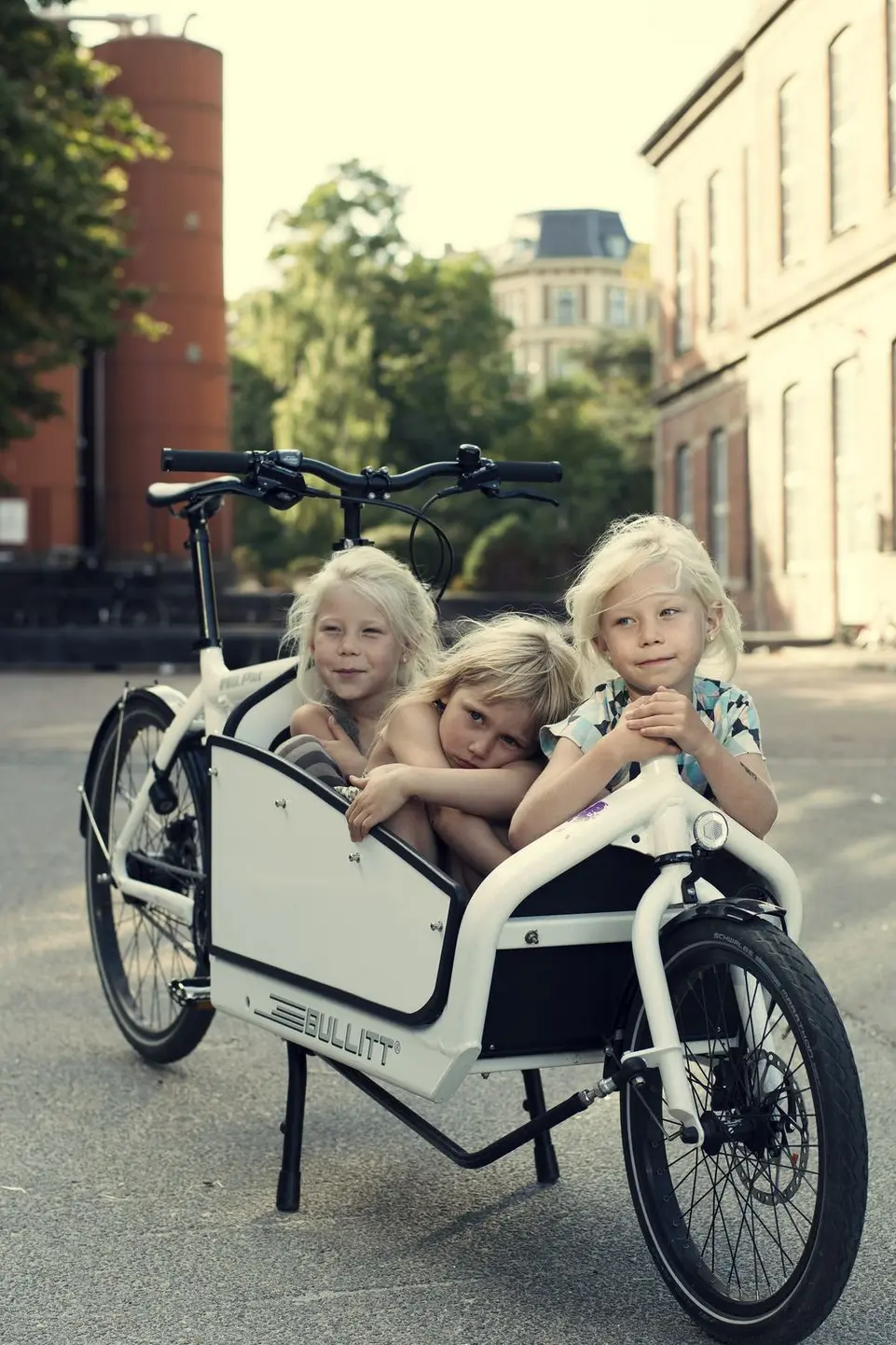 BULLITT & Bullitt X im Größenvergleich – zwei Lastenräder von Larry vs Harry nebeneinander im Studio, das X mit längerer Ladefläche. Drei Kinder entspannt im E-Bullitt von Larry vs Harry – chillige Nahaufnahme im Lastenrad.