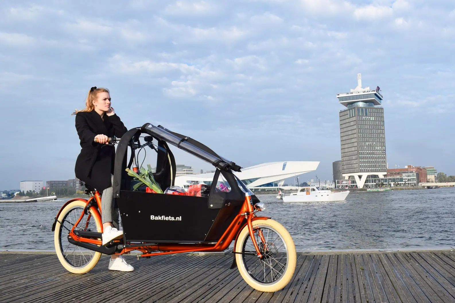 Bakfiets in Amsterdam: Alltag mit Kind und Cargobike. Mutter fährt mit ihrem Bakfiets und Kind durch Amsterdam – typischer Großstadtalltag auf drei Rädern.