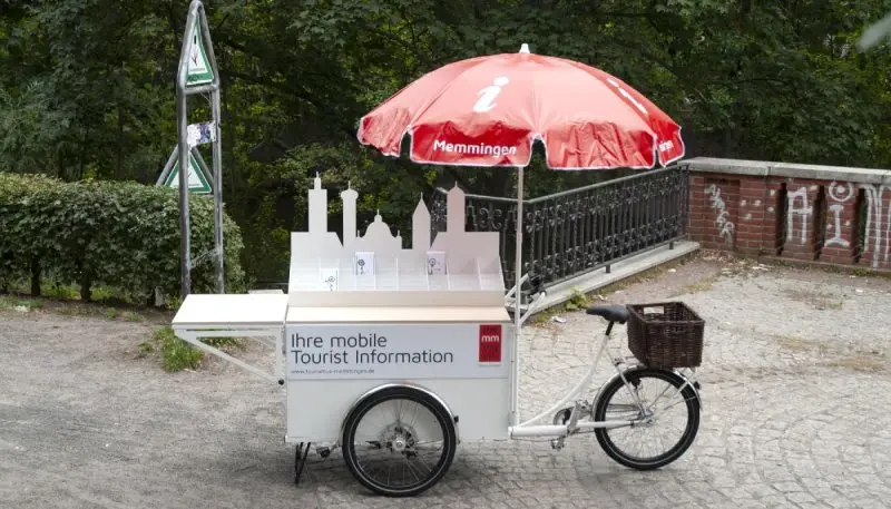 Christiania-Dreirad als mobiler Infostand – mit Sonnenschirm, Tischfläche und Präsentationsmaterial.