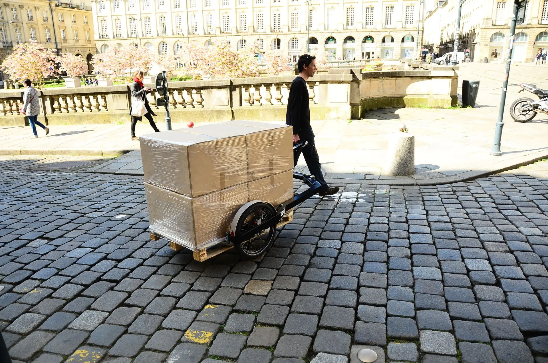 Fleximodal BicyLift – Paletten einfach ziehen oder fahren. Person zieht einen beladenen Fleximodal-Palettenanhänger manuell hinter sich her.
