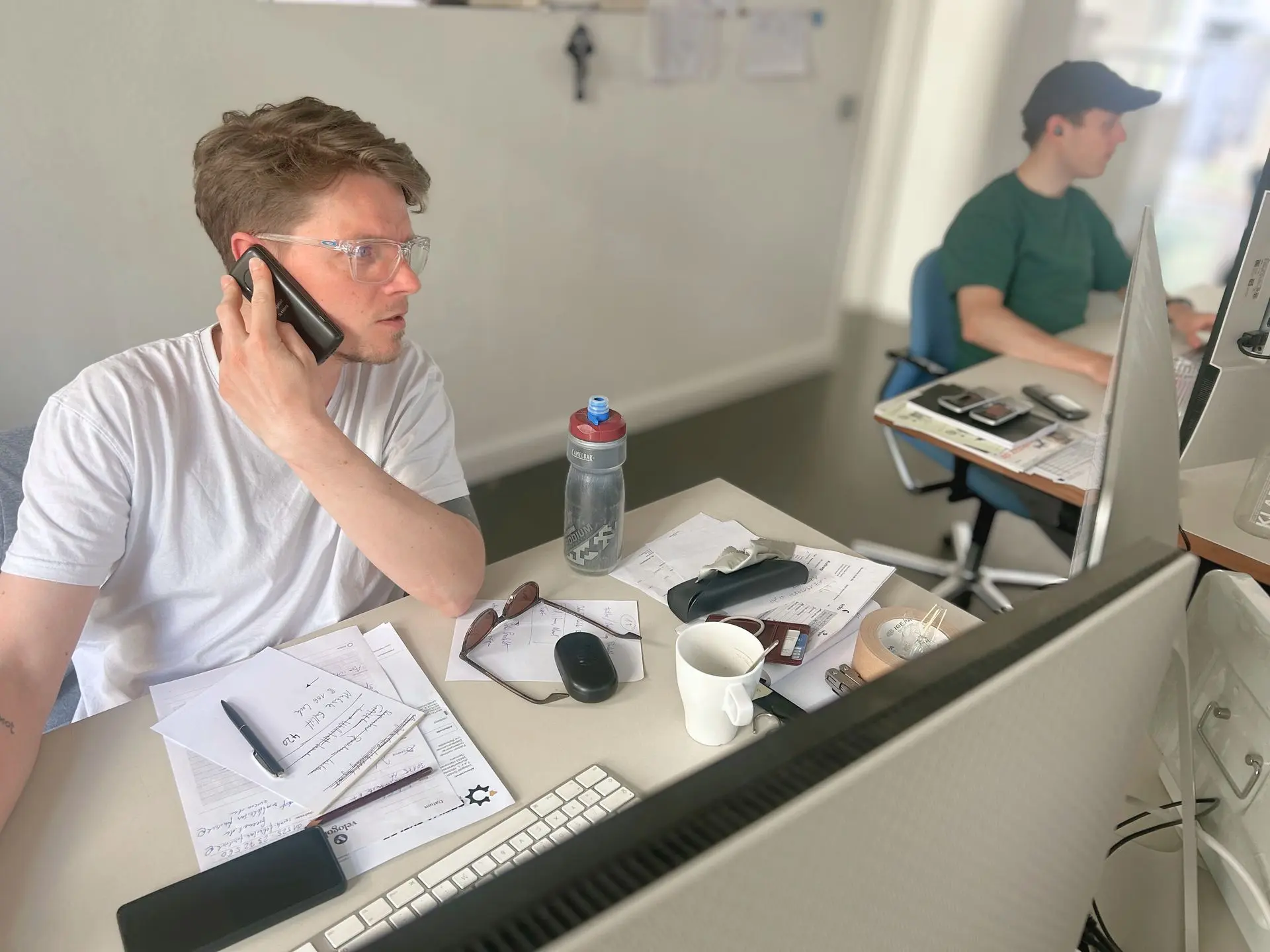 Ausbildung E-Commerce: Organisation, Onlineverkauf & Kundendialog bei Velogold Büroszene bei Velogold: Zwei Mitarbeitende am Telefon und vor Monitoren in der E-Commerce-Abteilung.